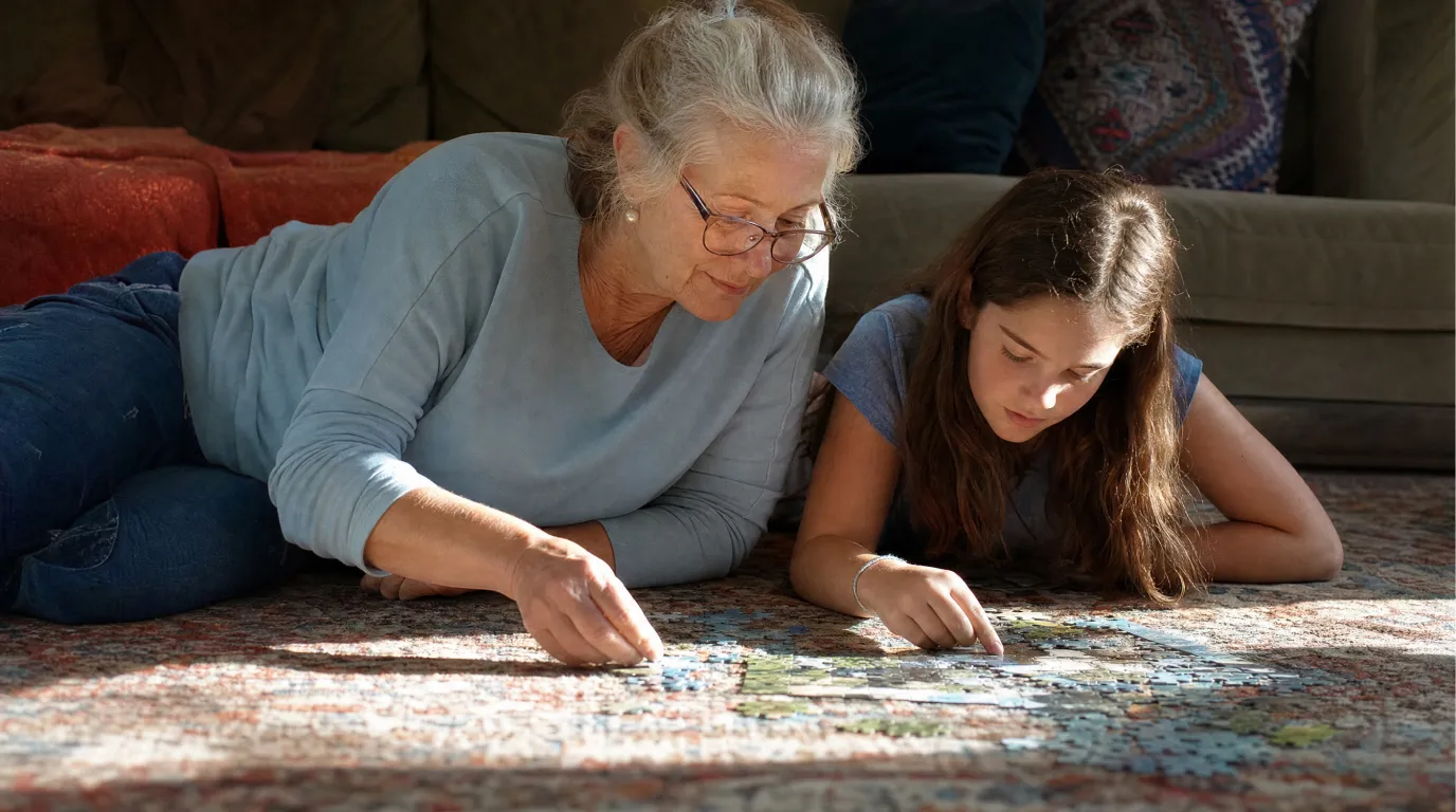 Woman doing a puzzle with her granddaughter on a living room rug.