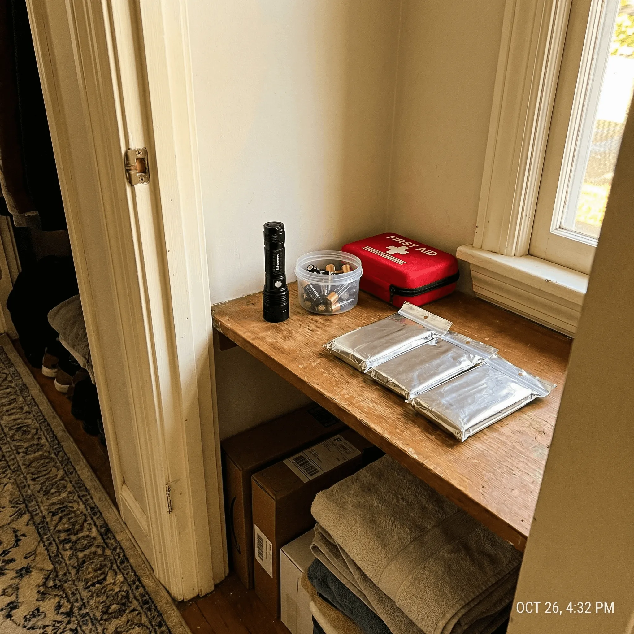 Emergency supplies neatly organized on a home closet shelf including thermal bivys and first aid kit