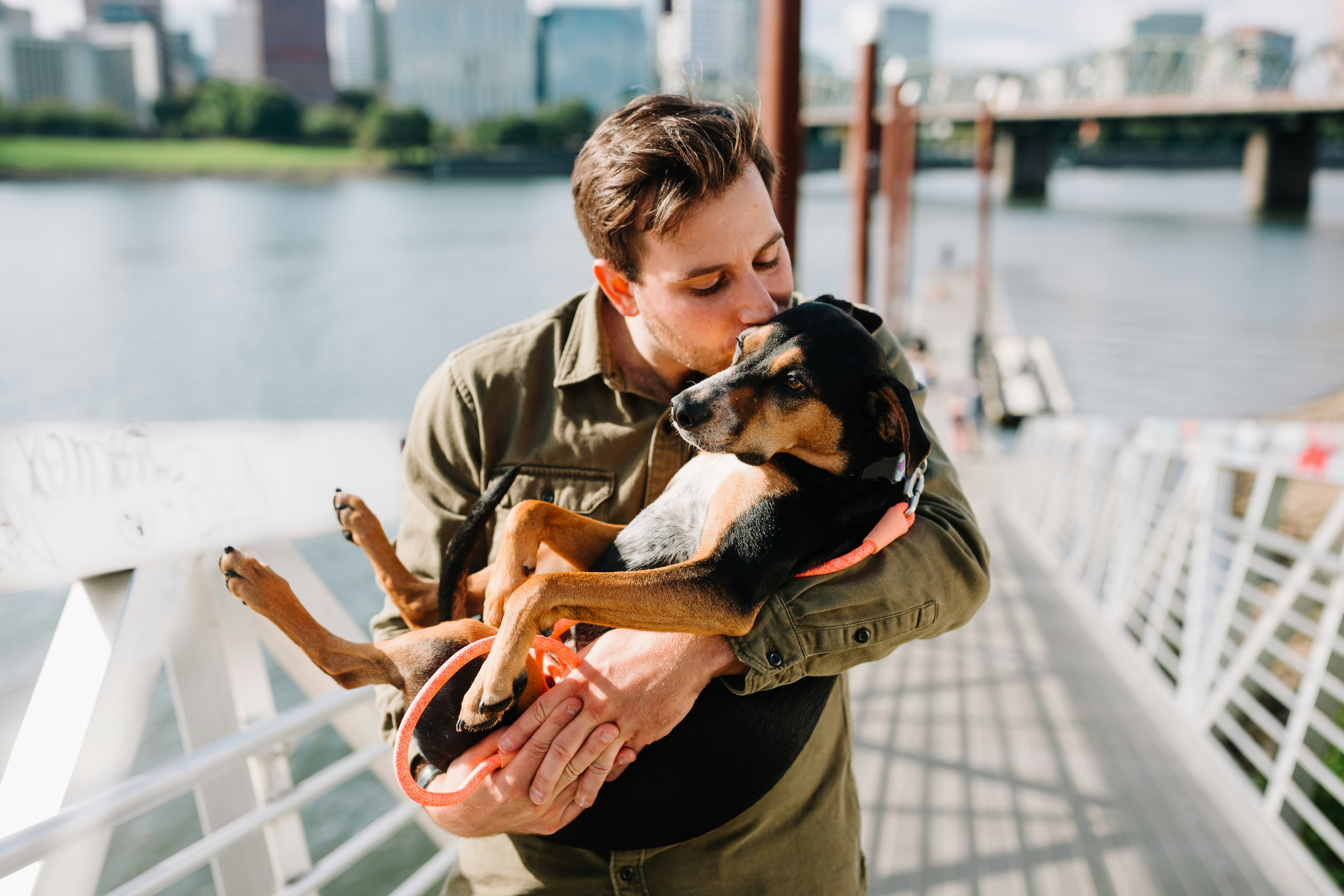 Woman laughing with her dog nuzzling her cheek