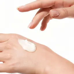 Woman applying Oestra hormone cream to hand — HRT article